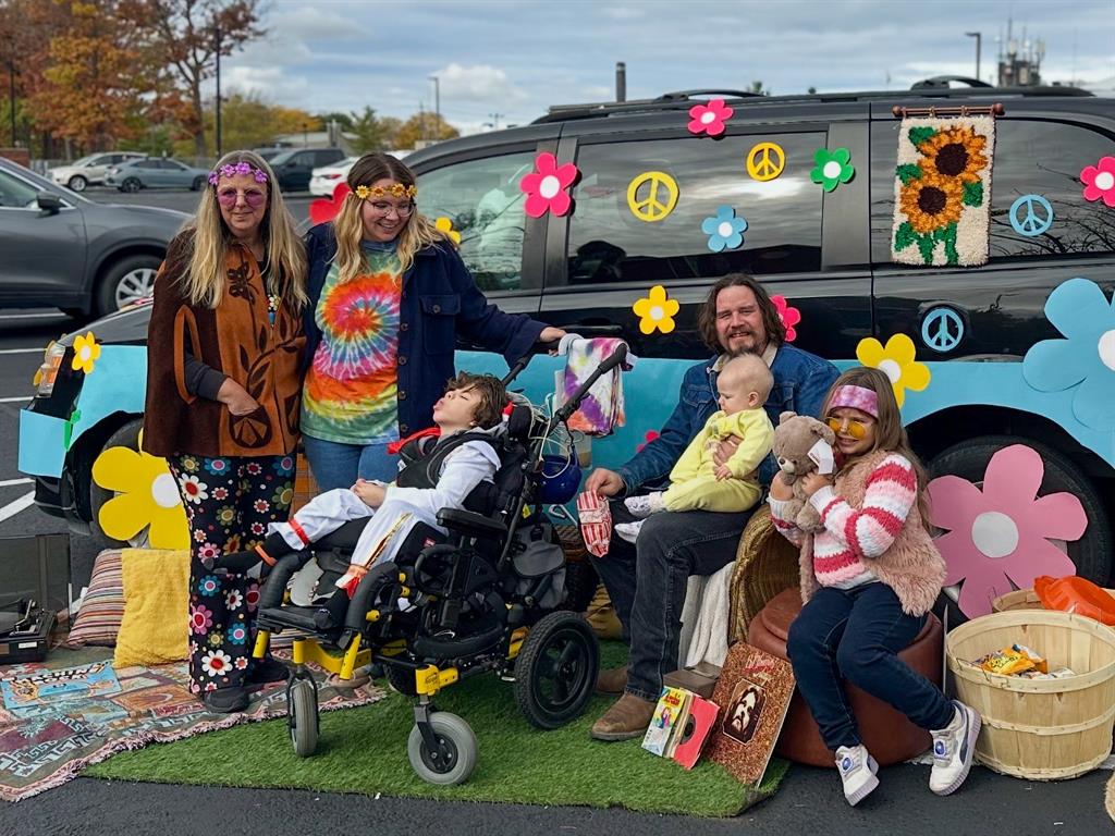 Family of six pose in front of 1970's-inspired mini van
